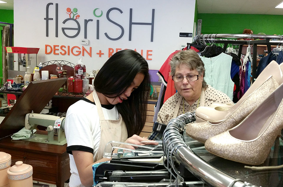 Two friends look at clothing on hangers at the Flerish store.