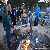 Campers and Staff roasting marsh mellows at fire.
