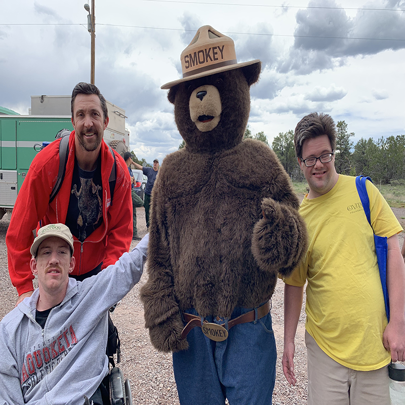 Smokey the Bear takes photo with several campers.